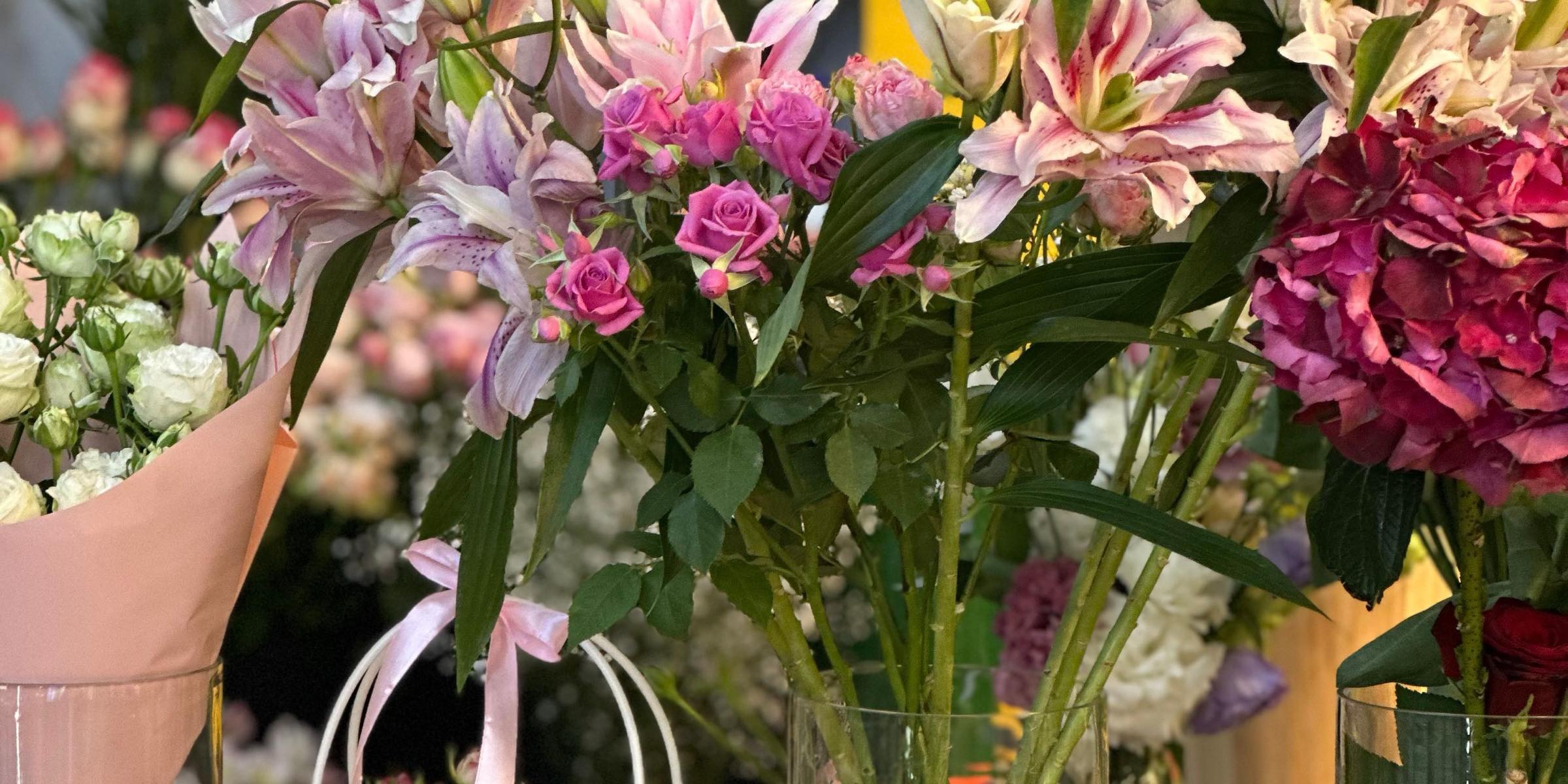 Lilien, Rosen und Hortensien in Glasvasen im Ladenregal