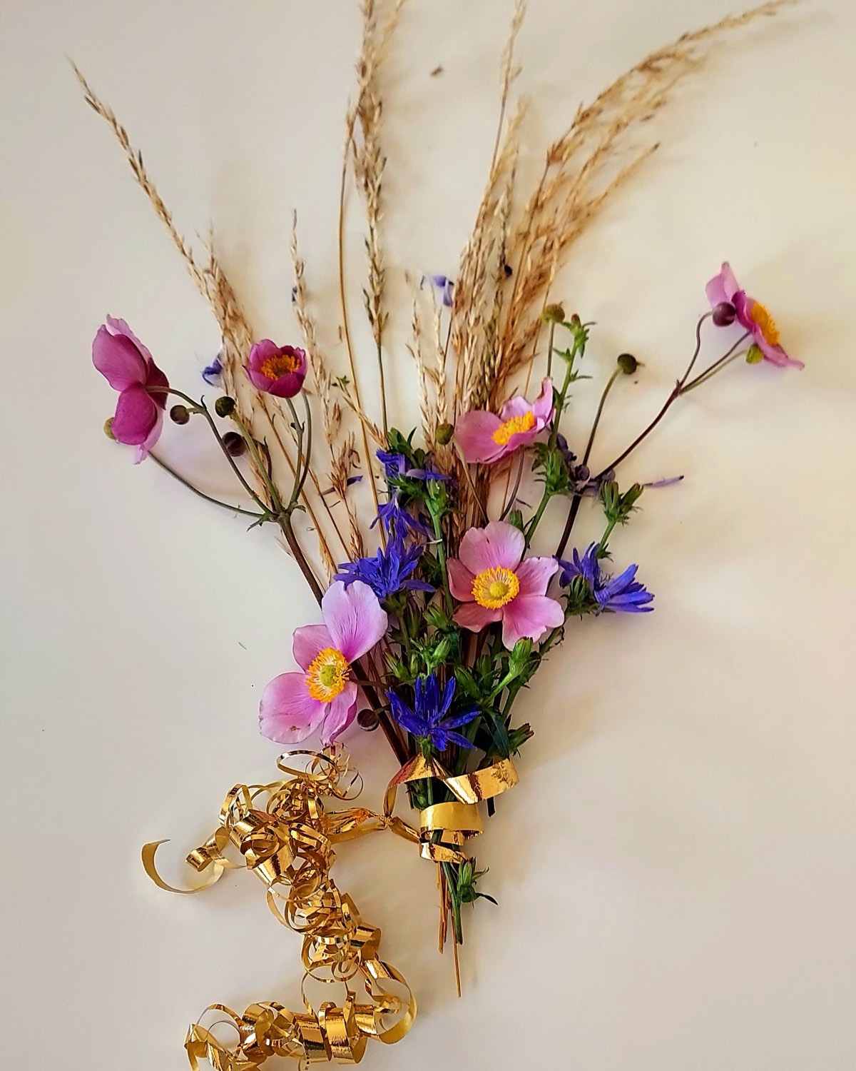 Wiesenblumenstrauß mit Gräsern und goldenem Band