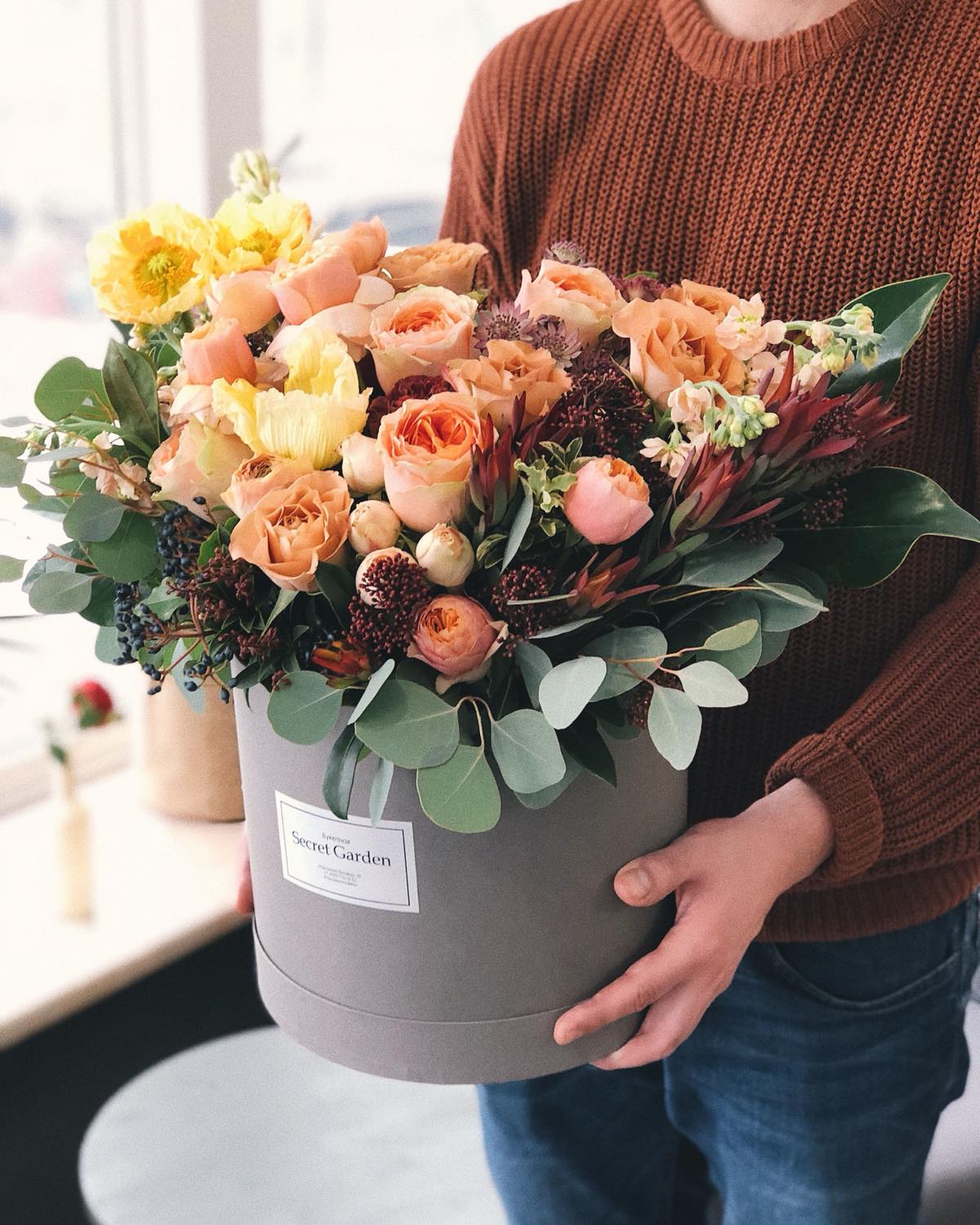 Pfirsichfarbene Rosen und Eukalyptus in einer runden Hutschachtel